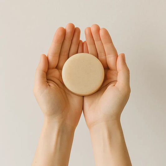 des mains en coupe tenant un savon solide rond dans une ambiance minimaliste
